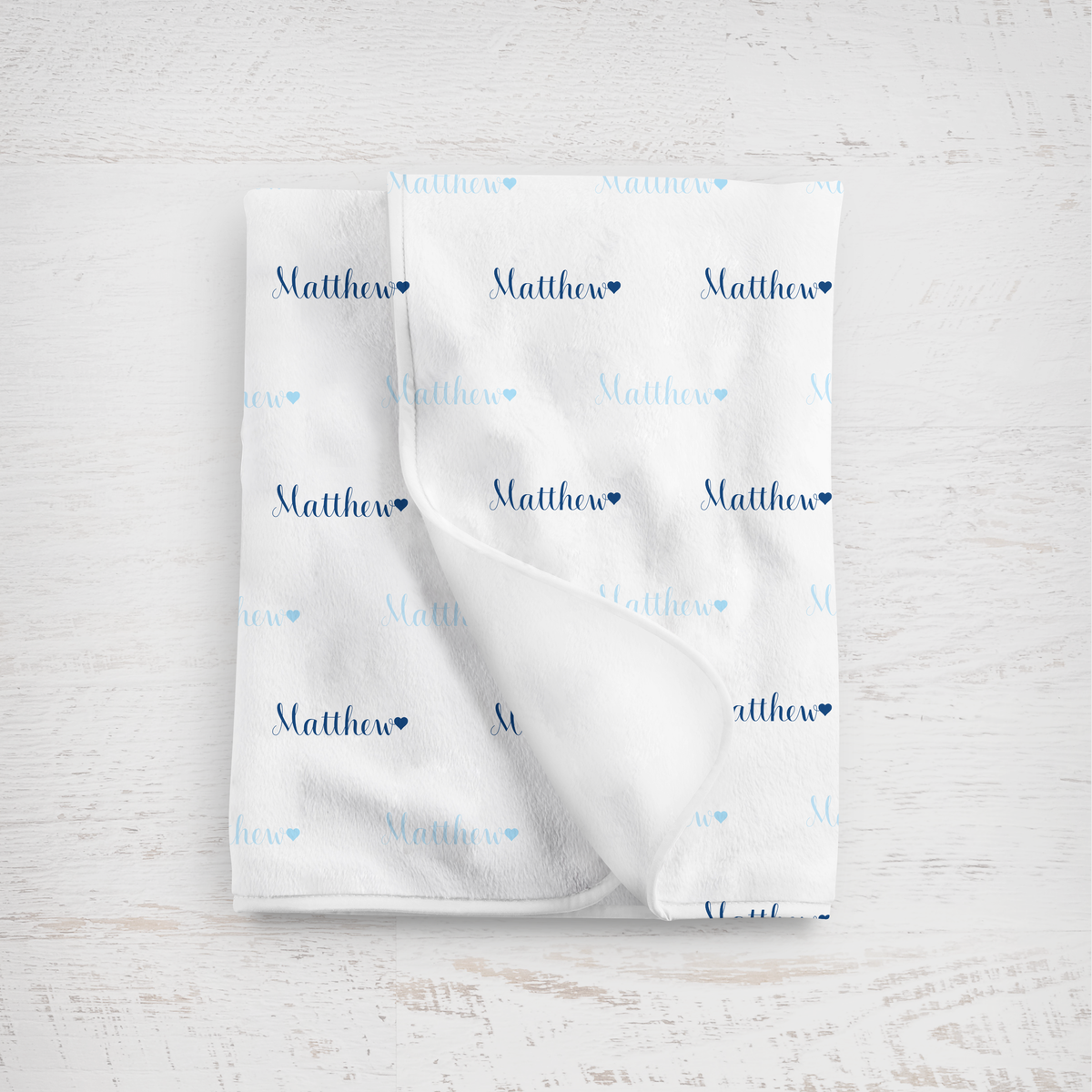 White blanket with name printed repeatedly on a light wooden surface