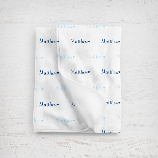 White blanket with name printed repeatedly on a light wooden surface