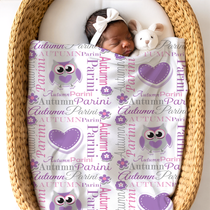 Newborn baby wrapped in an owl blanket lying in a woven basket.