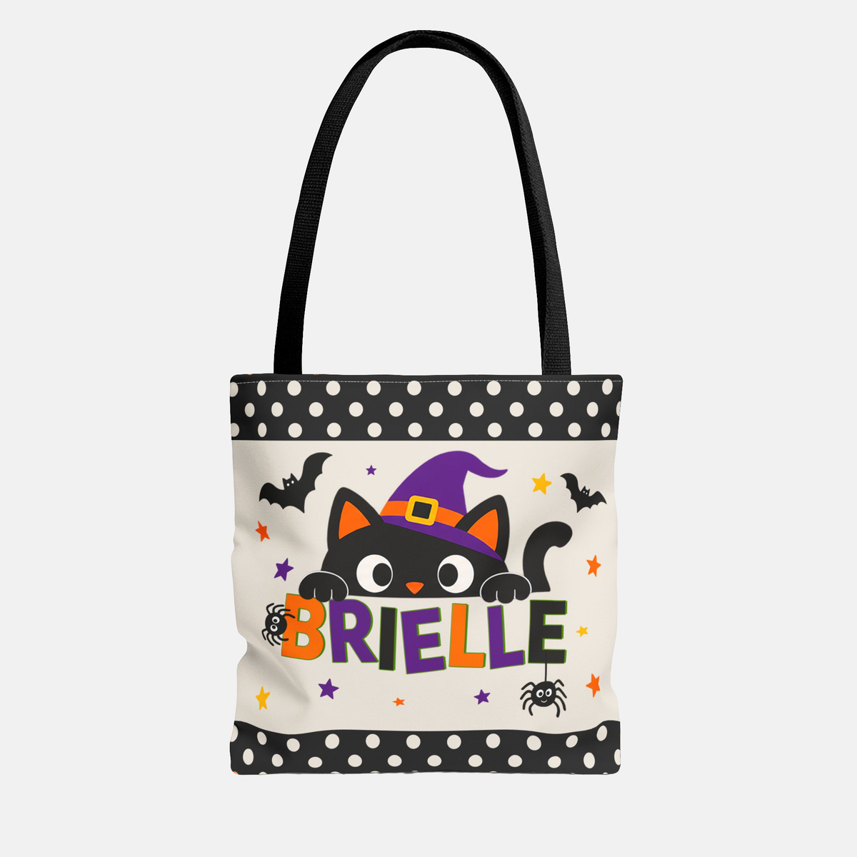 A white canvas tote bag with black handles, featuring a Halloween-themed graphic of a black cat in a purple witch hat peeking behind the name 'BRIELLE' in colorful letters. The bag has black and white polka dot trim at the top and bottom.