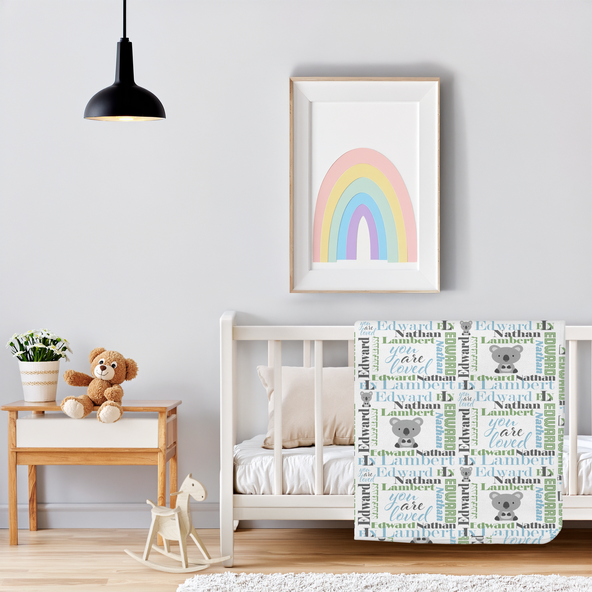 A personalized baby blanket featuring the name 'Edward' with 'B' monograms, cute cartoon koalas, and the phrase 'You Are Loved' in a pastel rainbow-themed nursery setting.