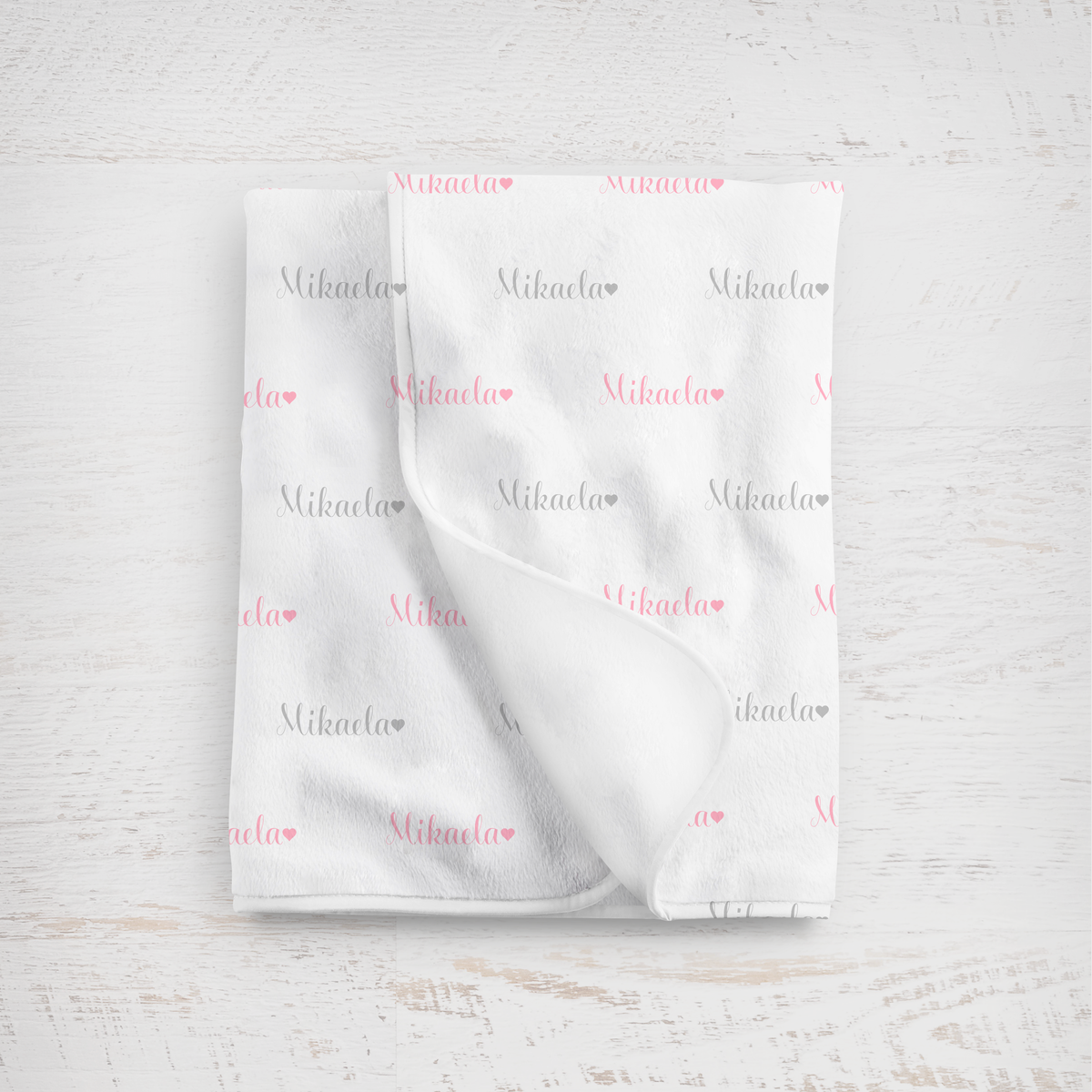 White blanket with name printed repeatedly on a light wooden surface