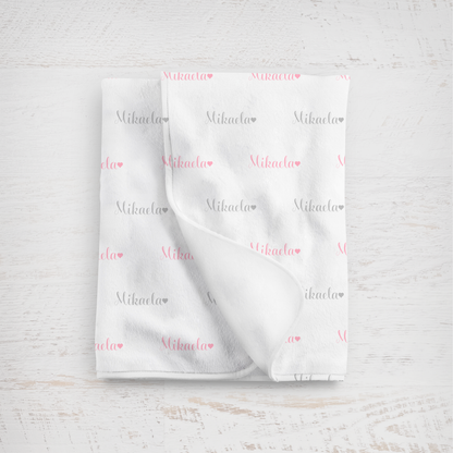 White blanket with name printed repeatedly on a light wooden surface