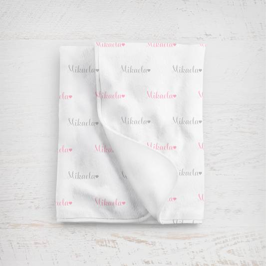 White blanket with name printed repeatedly on a light wooden surface